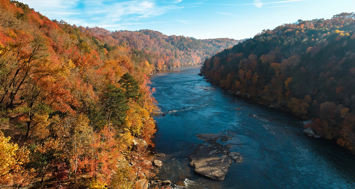 High hills with trees displaying fall colors surround the Cumberland River